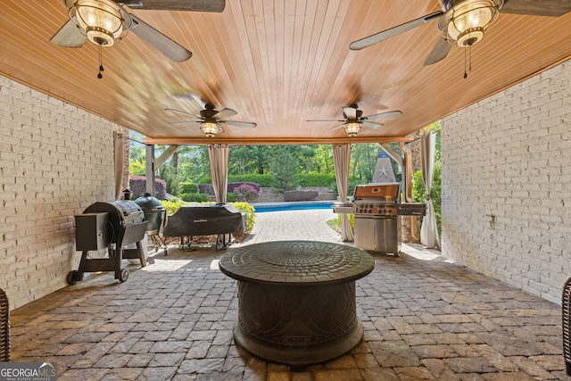 view of patio / terrace with a ceiling fan, a fire pit, an outdoor pool, and grilling area
