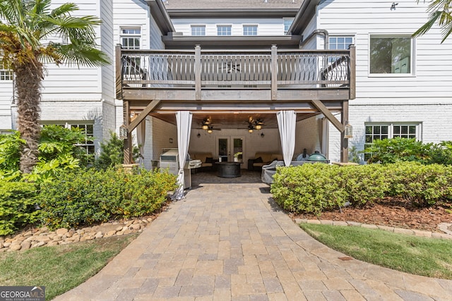 exterior space featuring brick siding, a wooden deck, a patio area, french doors, and a ceiling fan