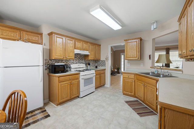 kitchen with a sink, under cabinet range hood, a wealth of natural light, and white appliances