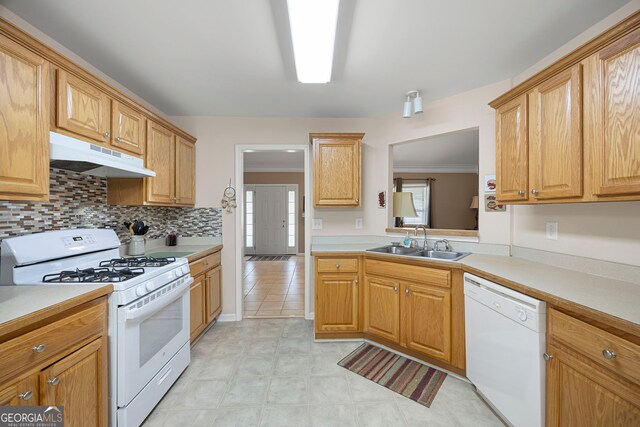 kitchen with a sink, under cabinet range hood, white appliances, and light countertops