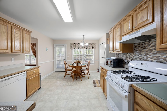kitchen featuring light countertops, baseboards, a notable chandelier, under cabinet range hood, and white appliances