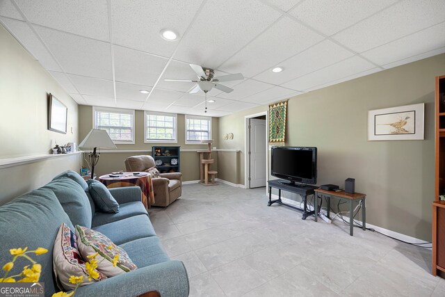living area featuring baseboards, a ceiling fan, light tile patterned flooring, and a paneled ceiling