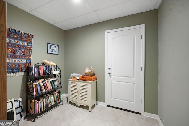 game room with tile patterned floors, baseboards, and a paneled ceiling