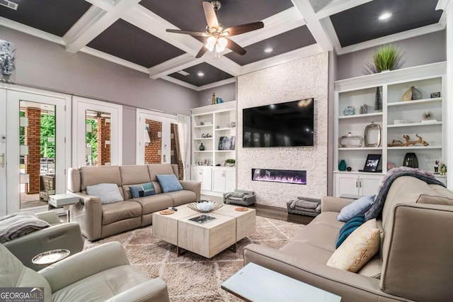 living room featuring wood finished floors, beamed ceiling, a large fireplace, a ceiling fan, and coffered ceiling