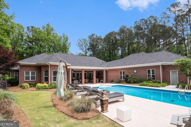 outdoor pool featuring a lawn and a patio area