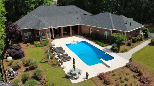 pool featuring a diving board, a yard, and a patio area
