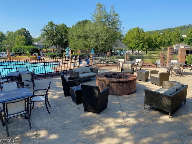 view of patio / terrace featuring a community pool, fence, and an outdoor living space with a fire pit