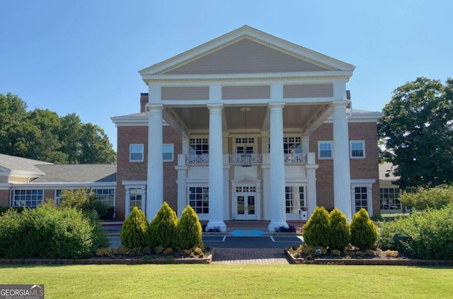 greek revival inspired property with a front lawn, a balcony, and french doors