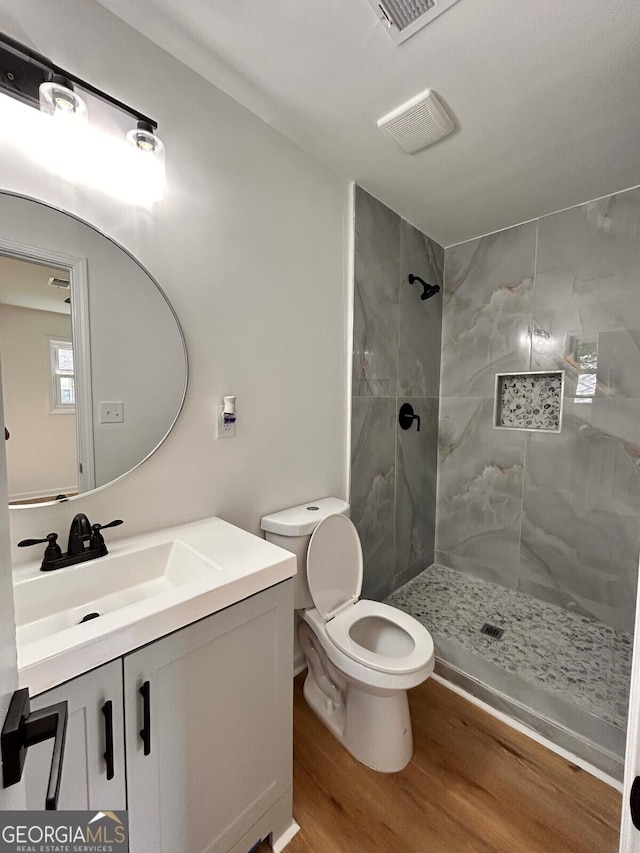 4074 Green Hawk Trl, Decatur, GA 30035 - bathroom with wood finished floors, a tile shower, vanity, and toilet