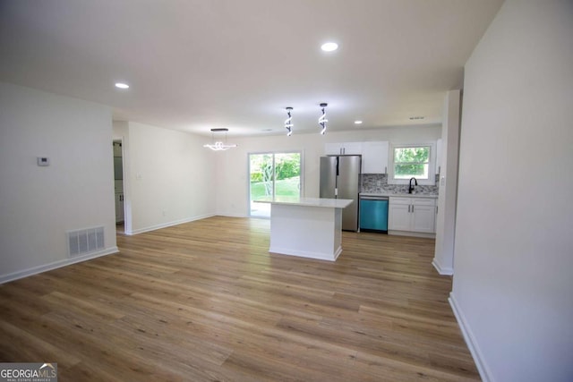 kitchen with visible vents, freestanding refrigerator, dishwashing machine, white cabinets, and a sink