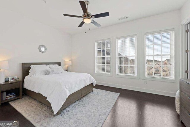 bedroom with baseboards, a ceiling fan, dark wood-type flooring, and visible vents
