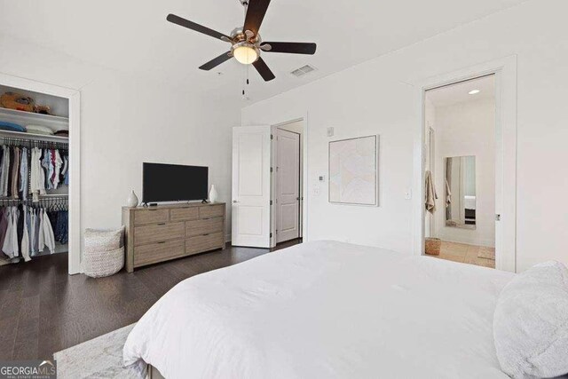 bedroom with ceiling fan, a walk in closet, wood finished floors, visible vents, and a closet