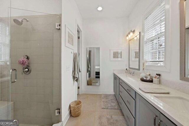 full bathroom with a sink, tile patterned floors, a shower stall, and double vanity