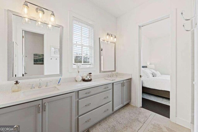 ensuite bathroom with tile patterned flooring, a sink, ensuite bathroom, and double vanity