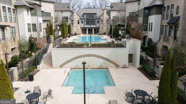 pool featuring fence, stairs, and a patio