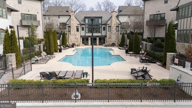 community pool featuring a patio, fence, and a residential view