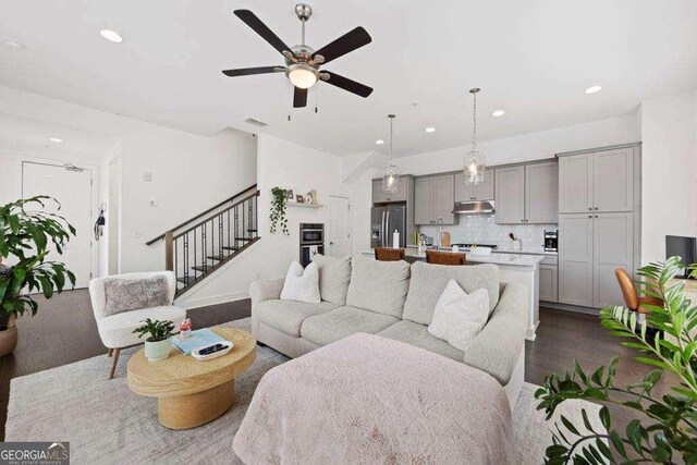 living room featuring recessed lighting, a ceiling fan, dark wood finished floors, and stairs