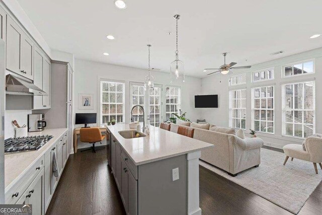 kitchen featuring a sink, stainless steel gas cooktop, recessed lighting, under cabinet range hood, and gray cabinetry