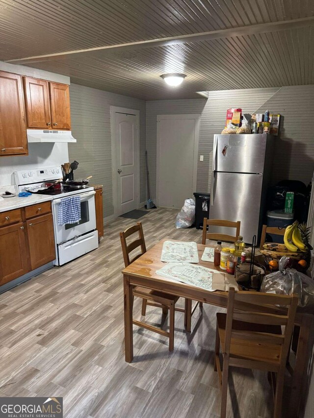kitchen with brown cabinets, white electric range oven, freestanding refrigerator, light wood-type flooring, and under cabinet range hood