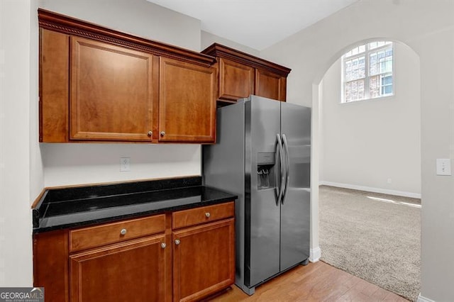 735 Scenic Creek Dr, Lawrenceville, GA 30046 - kitchen featuring stainless steel fridge, arched walkways, brown cabinets, light wood-style floors, and dark stone counters