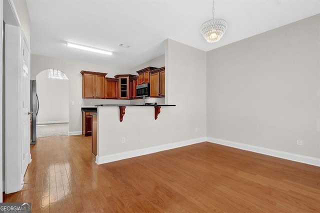 735 Scenic Creek Dr, Lawrenceville, GA 30046 - kitchen featuring arched walkways, appliances with stainless steel finishes, wood finished floors, a breakfast bar, and a peninsula