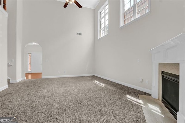 735 Scenic Creek Dr, Lawrenceville, GA 30046 - unfurnished living room with a towering ceiling, a ceiling fan, carpet floors, arched walkways, and a fireplace with flush hearth
