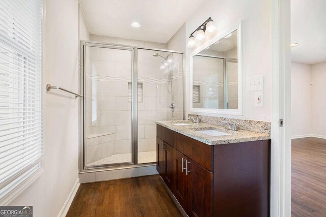 full bath with baseboards, a shower stall, a sink, and wood finished floors