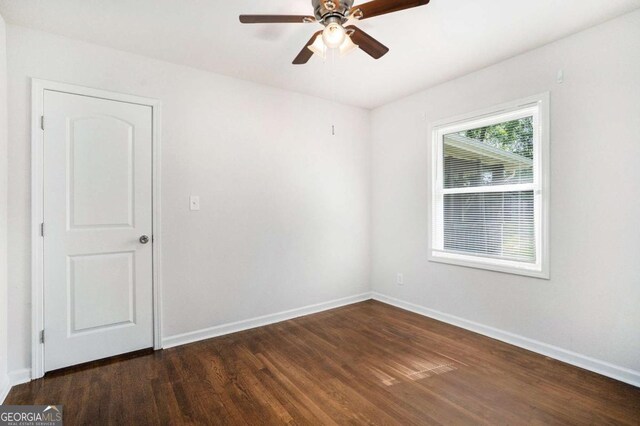 unfurnished room with dark wood-type flooring, a ceiling fan, and baseboards