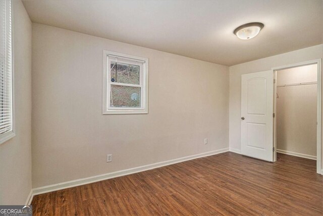 unfurnished bedroom featuring baseboards, wood finished floors, and multiple windows