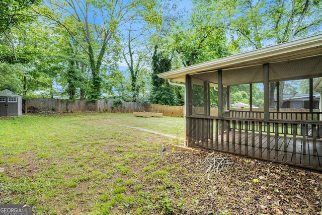 view of yard with a sunroom, a fenced backyard, a storage shed, and an outdoor structure