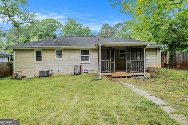 back of house with a lawn, brick siding, fence, and a sunroom