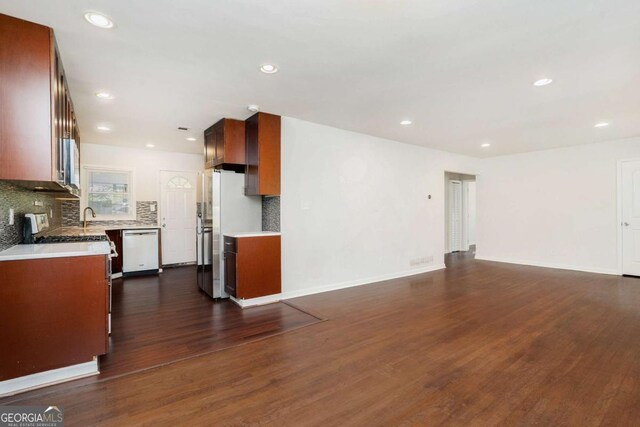 unfurnished living room featuring recessed lighting, baseboards, dark wood-style floors, and a sink