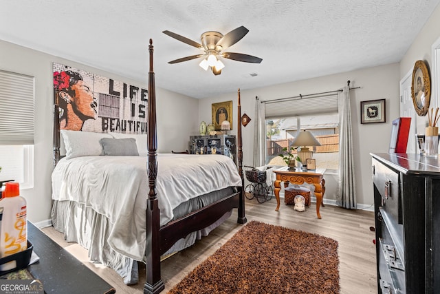 bedroom with a textured ceiling, ceiling fan, visible vents, and light wood-style flooring