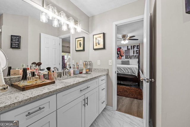 ensuite bathroom featuring vanity, ensuite bathroom, ceiling fan, and marble finish floor