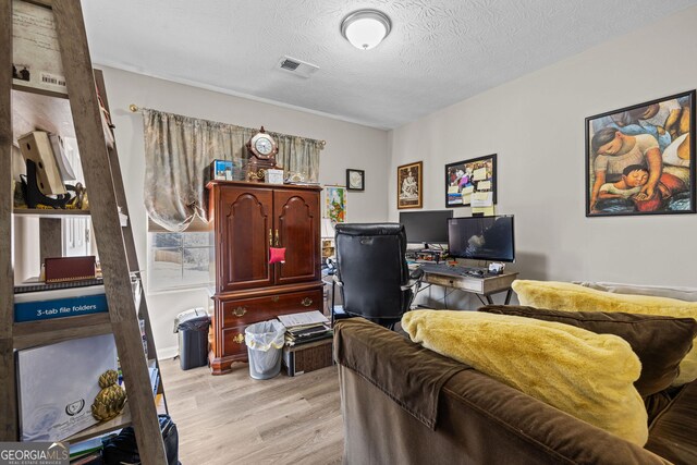 bedroom featuring light wood-style floors, a textured ceiling, and visible vents