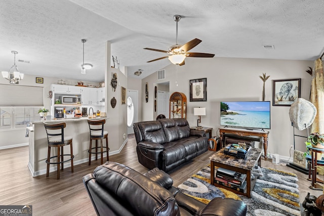 living area featuring visible vents, a textured ceiling, and wood finished floors