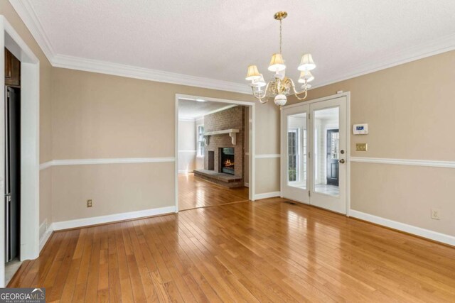 unfurnished dining area with crown molding, baseboards, an inviting chandelier, and light wood finished floors