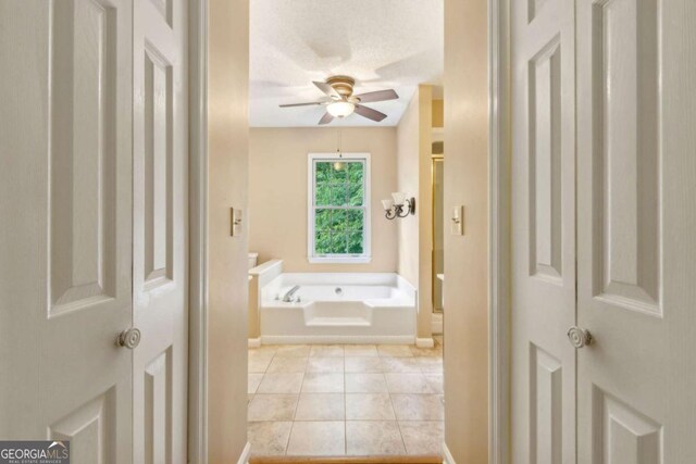 bathroom with a garden tub, tile patterned flooring, baseboards, ceiling fan, and walk in shower