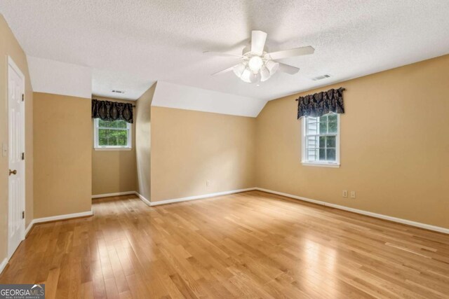 unfurnished room featuring a ceiling fan, a textured ceiling, visible vents, baseboards, and light wood-style flooring