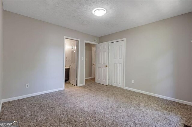 785 Redland Dr, Jonesboro, GA 30238 - unfurnished bedroom featuring light carpet, a textured ceiling, a closet, and connected bathroom