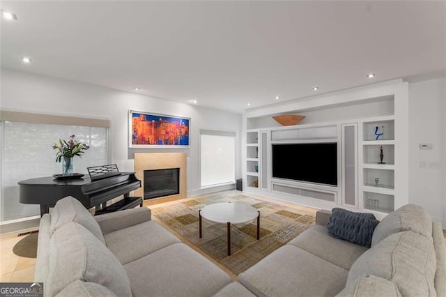 living room featuring built in shelves, a glass covered fireplace, recessed lighting, and baseboards