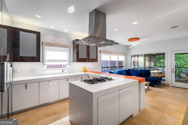 kitchen featuring island range hood, stainless steel gas stovetop, white cabinetry, light countertops, and recessed lighting
