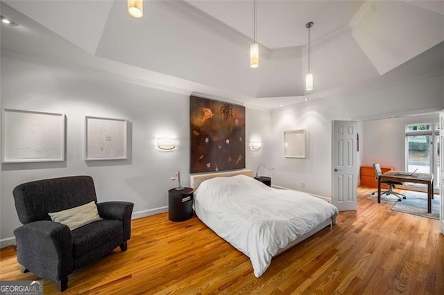 bedroom featuring wood finished floors, baseboards, ornamental molding, and a raised ceiling