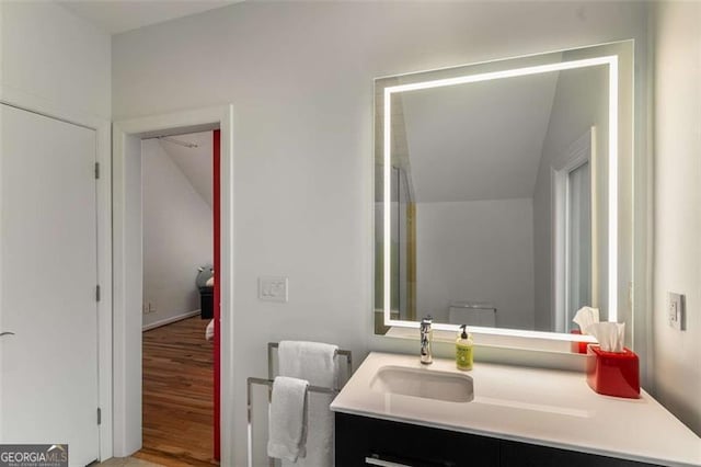 bathroom with vanity, lofted ceiling, and wood finished floors