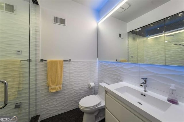 full bath featuring tile walls, vanity, a shower stall, and toilet