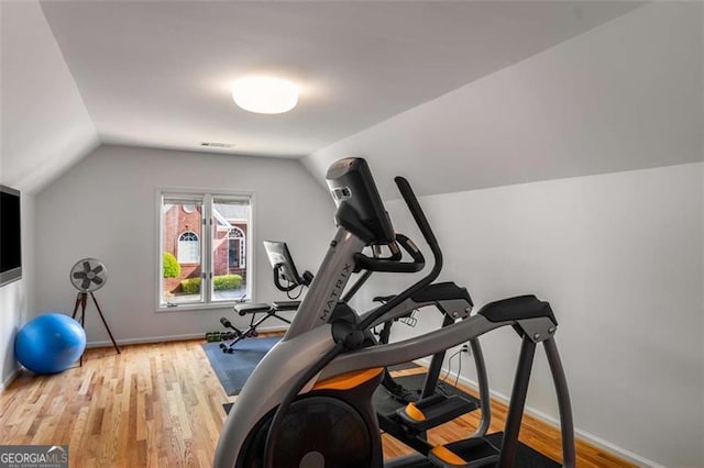 exercise area featuring vaulted ceiling, wood finished floors, and baseboards