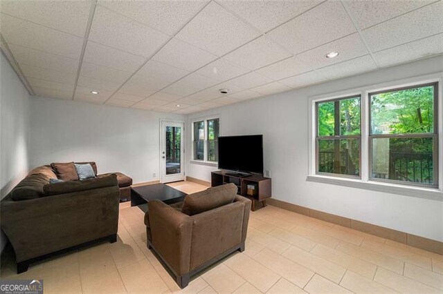 living room with a drop ceiling, baseboards, light tile patterned floors, and recessed lighting