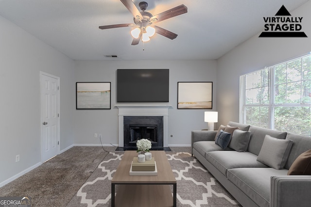 carpeted living area featuring ceiling fan, baseboards, and a fireplace with flush hearth