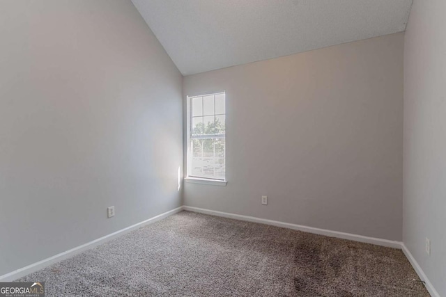 carpeted empty room with vaulted ceiling and baseboards
