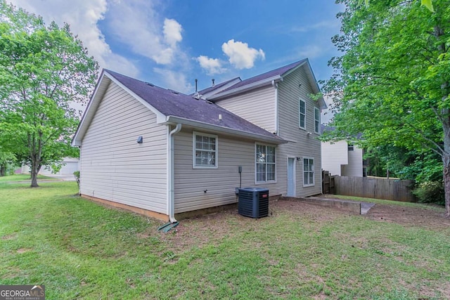 back of house with central AC unit and a shingled roof